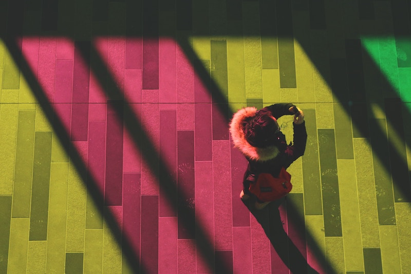 Woman walking on street with diagonal lights around her.