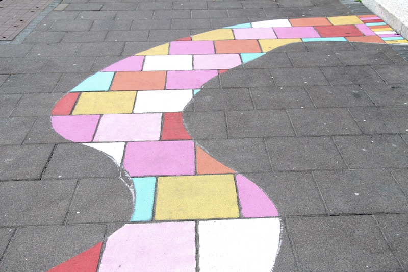 Brown brick path, with colorful winding path painted over the bricks.