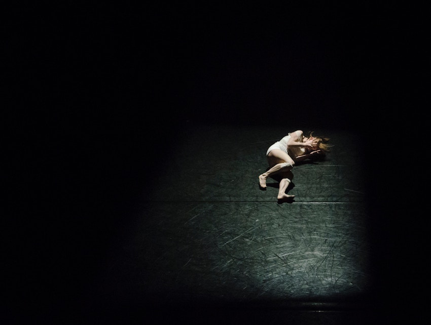 girl lying on stage alone in a spotlight