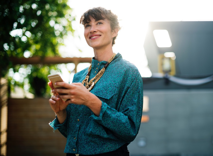 woman looking up from smartphone smiling