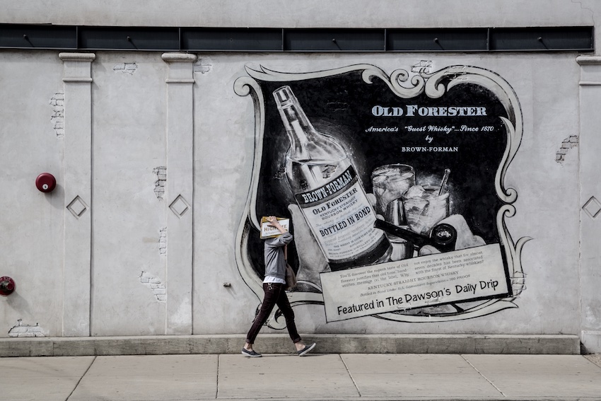 man walking by old advertisement