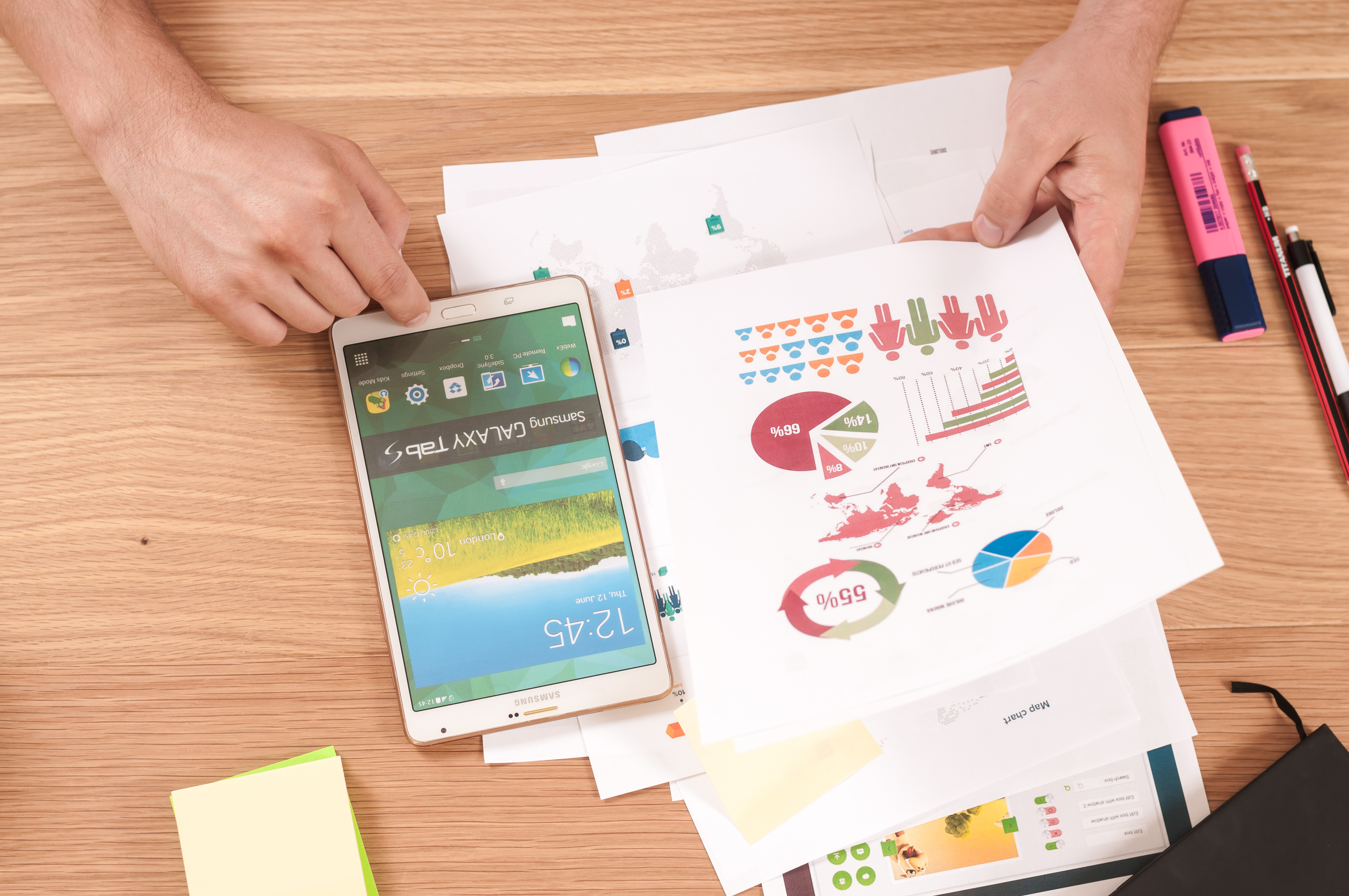 overhead shot of person with smart phone and printed graphs and charts