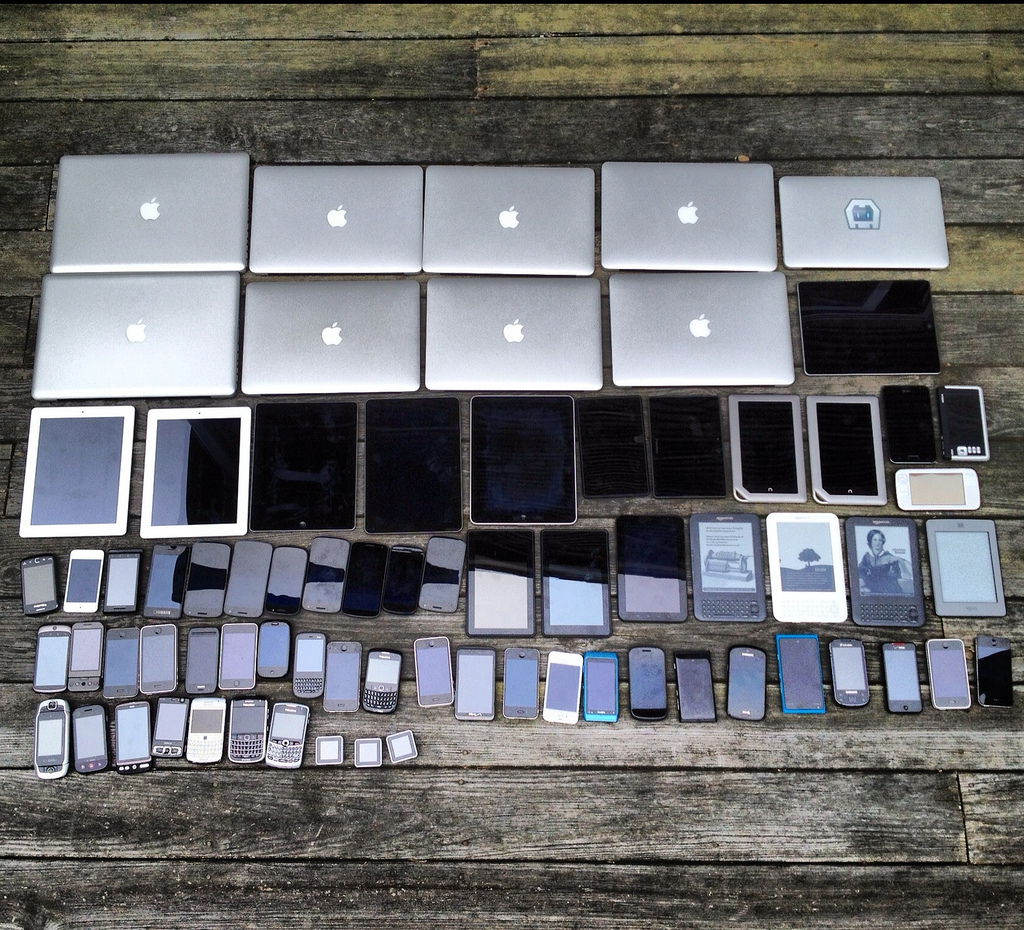 image containing a large collection of electronic devices ranging from laptops to smart phones of all brands shapes and sizes