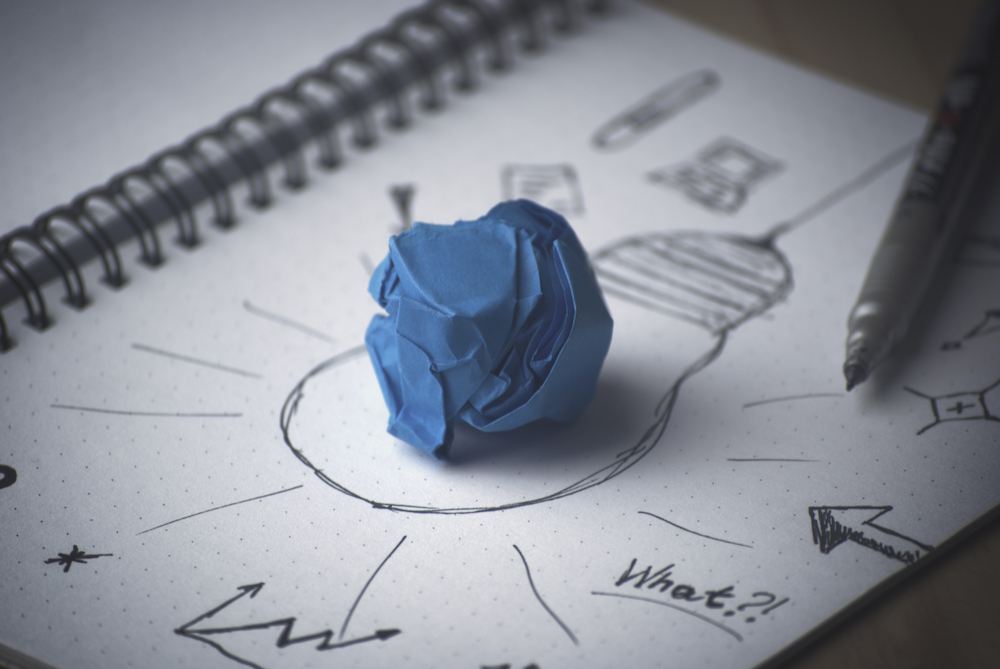 paper with notes and lightbulb drawn on with crumpled paper on top