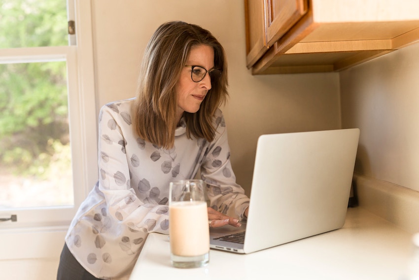 woman browsing on computer while drinking milk