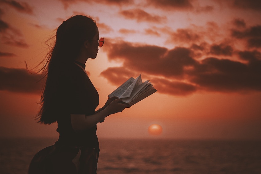 woman reading a book on the beach