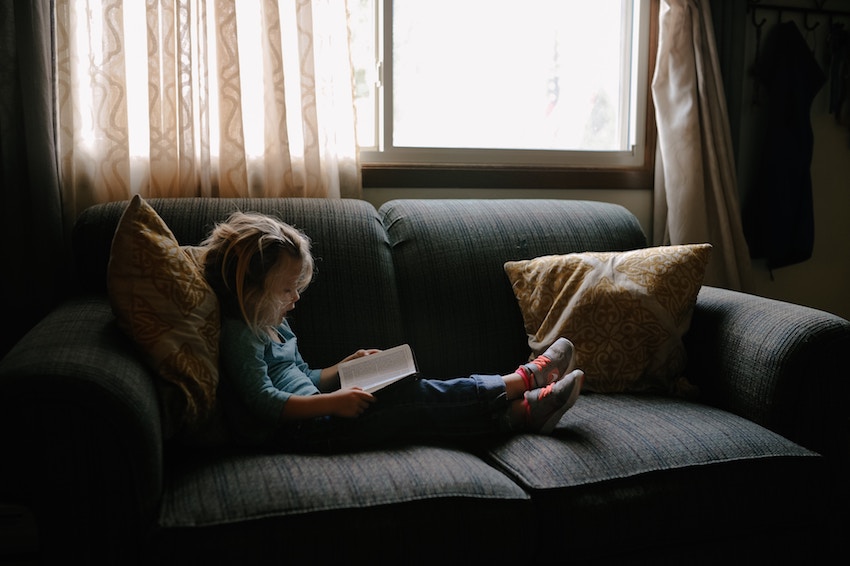 girl reading book on a couch