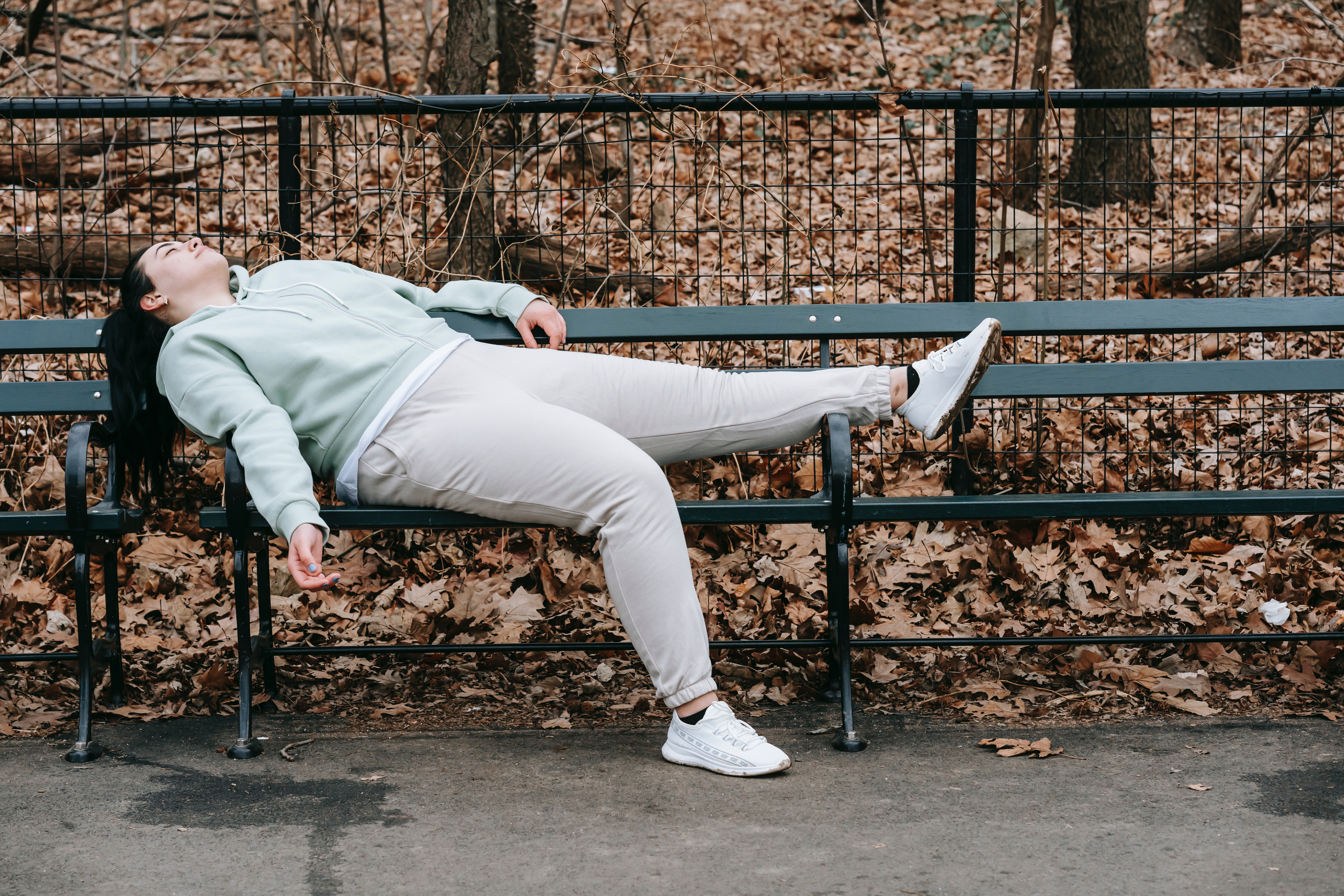 Tired lady laying on a bench.