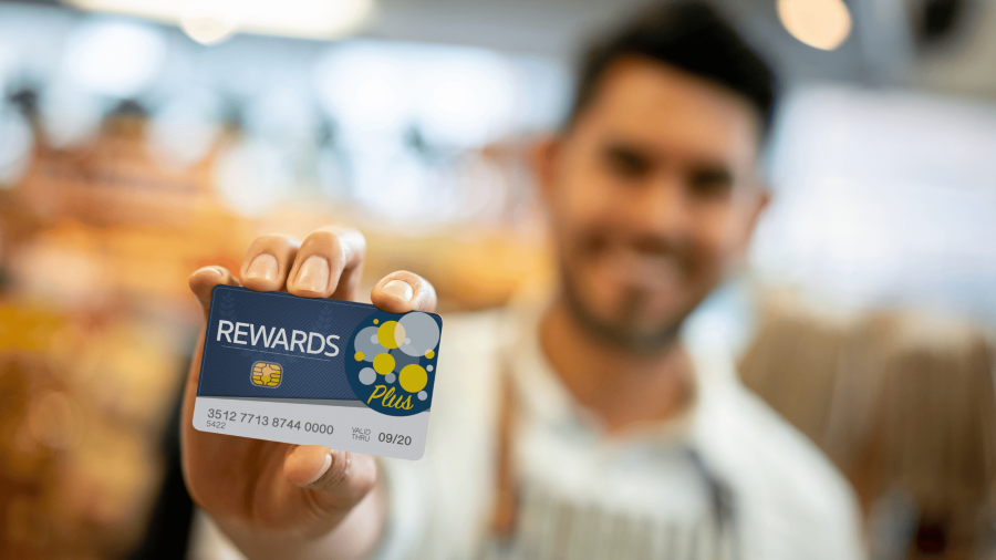 A grocery store clerk holding a rewards card.