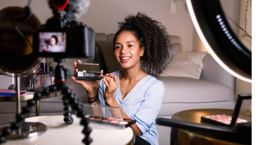 A women doing a make-up tutorial in front of her camera at home.