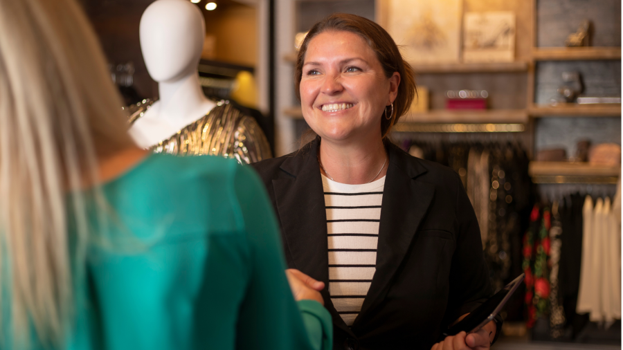 A manager/owner shaking someones hand smiling.