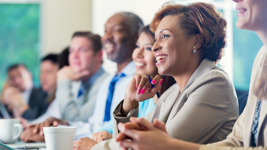 A woman sitting on a board with other people smiling and listening.