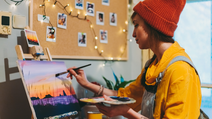 A woman standing in front of a easel painting